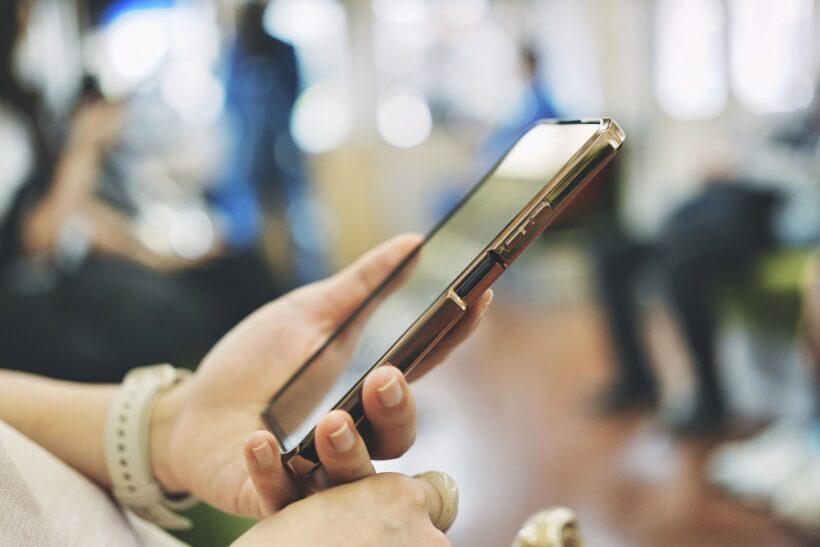 電車内でスマホを見ている人の手の写真