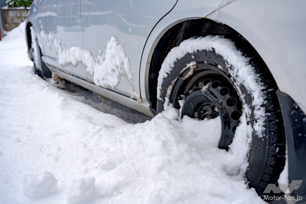 タイヤが雪に埋もれている車の写真