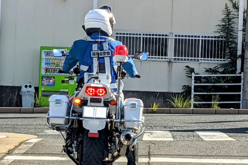 右足をついて信号待ちをする白バイ