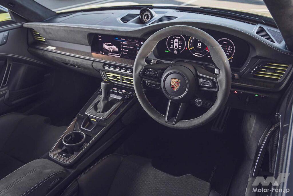 992II世代になりGT3のメーターパネルもフルデジタルに。試乗車は右ハンドルの7速DCT仕様で、オプションのヴァイザッハパッケージ（339万円）、クラブスポーツパッケージ（無償）を装着。フロントリッドやルーフなどがカーボン製になるほか、インテリアは一面バックスキン調の合成皮革でスポーティな装いに。ロールケージや6点式シートベルトも含まれる。エンジンフードはなく、オイルと冷却水の注入口を覆うフタが開くのみだ。
