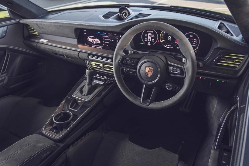992II世代になりGT3のメーターパネルもフルデジタルに。試乗車は右ハンドルの7速DCT仕様で、オプションのヴァイザッハパッケージ（339万円）、クラブスポーツパッケージ（無償）を装着。フロントリッドやルーフなどがカーボン製になるほか、インテリアは一面バックスキン調の合成皮革でスポーティな装いに。ロールケージや6点式シートベルトも含まれる。エンジンフードはなく、オイルと冷却水の注入口を覆うフタが開くのみだ。