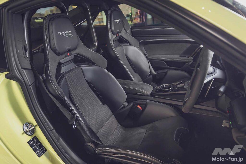 992II世代になりGT3のメーターパネルもフルデジタルに。試乗車は右ハンドルの7速DCT仕様で、オプションのヴァイザッハパッケージ（339万円）、クラブスポーツパッケージ（無償）を装着。フロントリッドやルーフなどがカーボン製になるほか、インテリアは一面バックスキン調の合成皮革でスポーティな装いに。ロールケージや6点式シートベルトも含まれる。エンジンフードはなく、オイルと冷却水の注入口を覆うフタが開くのみだ。