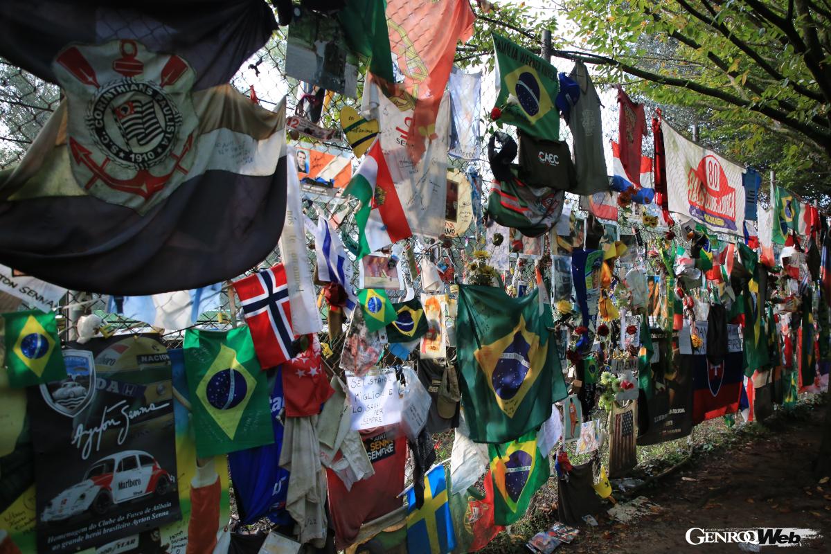 モニュメントの脇のコースとの境界になるフェンスにはセナの母国ブラジルの国旗や花、あるいは当時の活躍をリスペクトするメッセージが添えられていた。