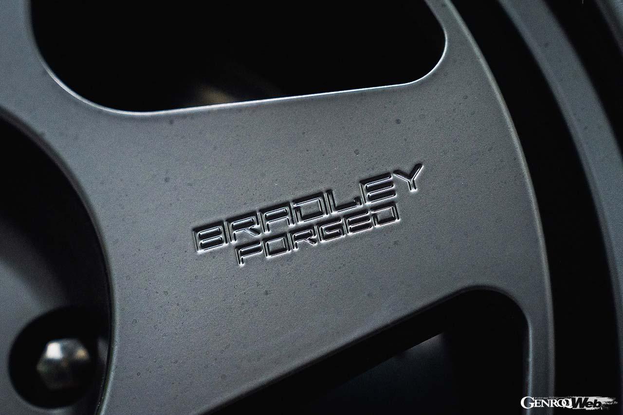 ブラッドレーフォージド匠は日本最高峰の鍛造製法を用いて生産される。リム部は鍛造素材をローラーで引き裂きながら圧延する裂開製法を採用。より薄く靭く鍛え上げられ高強度と軽量化を両立させる。この個体にはボディカラーと調和するマットシャドーブラックが装着される。ほかにマットディープグレイ、マットチタンブロンズがある。骨太スポークの一端には「BRADLEY FORGED」が掘文字加工されている。